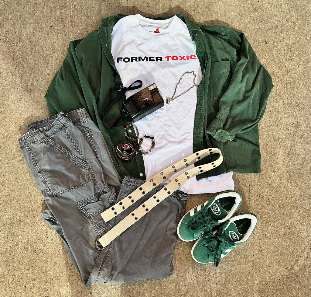 Former Toxic minimalist logo tee styled with green overshirt, gray cargo pants, green Adidas sneakers, camera, jewelry, and belt for a streetwear outfit layout.