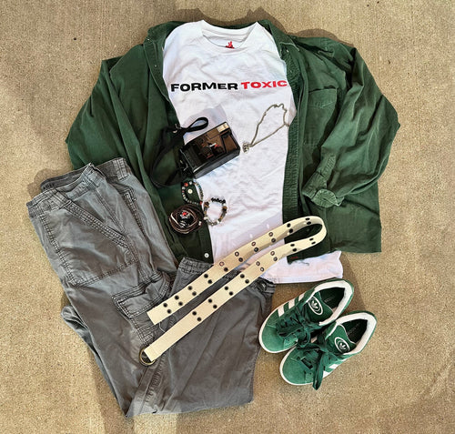 Former Toxic minimalist logo tee styled with green overshirt, gray cargo pants, green Adidas sneakers, camera, jewelry, and belt for a streetwear outfit layout.