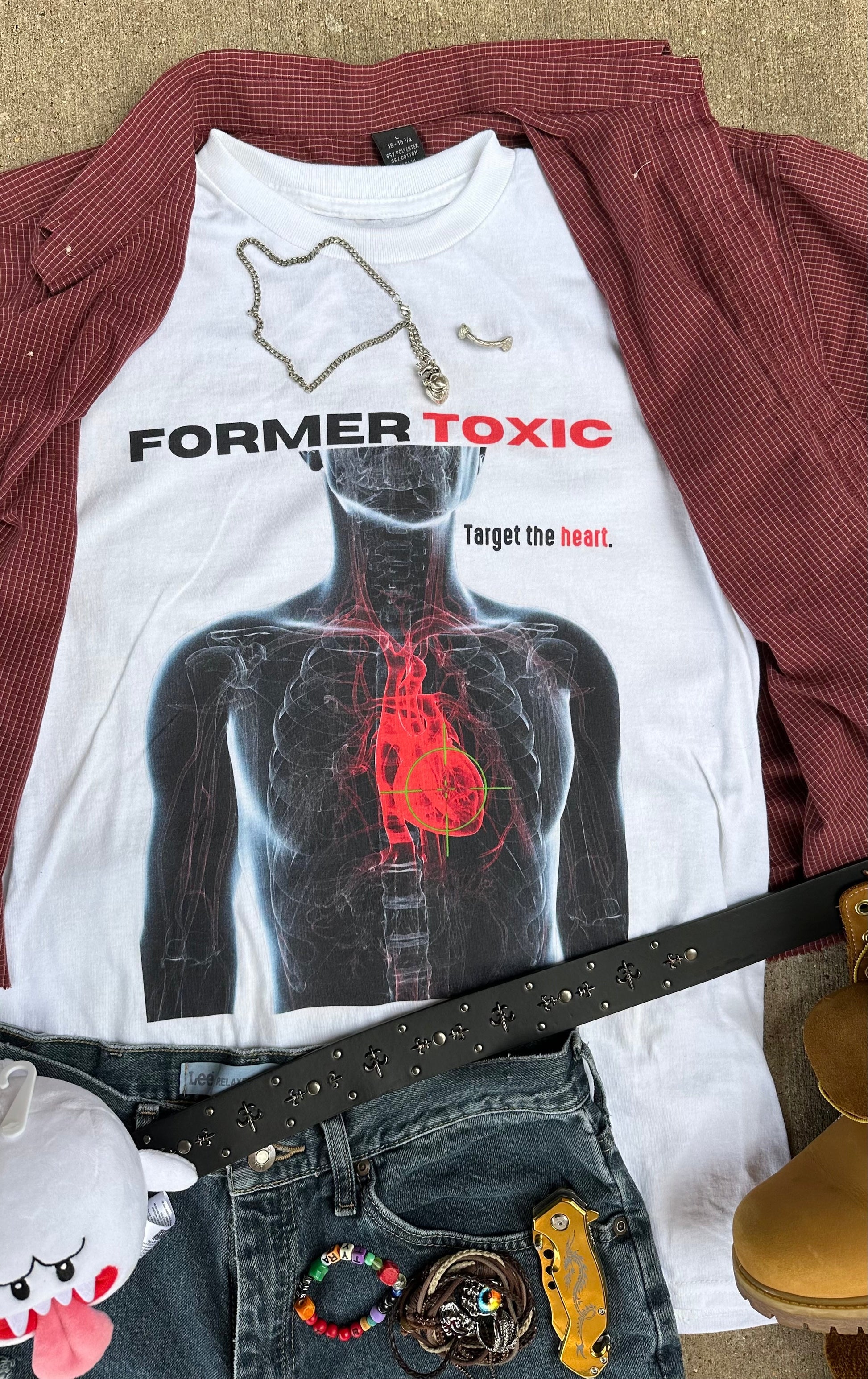 White t-shirt with graphic design and text 'Former Toxic' on a red jacket and jeans background.