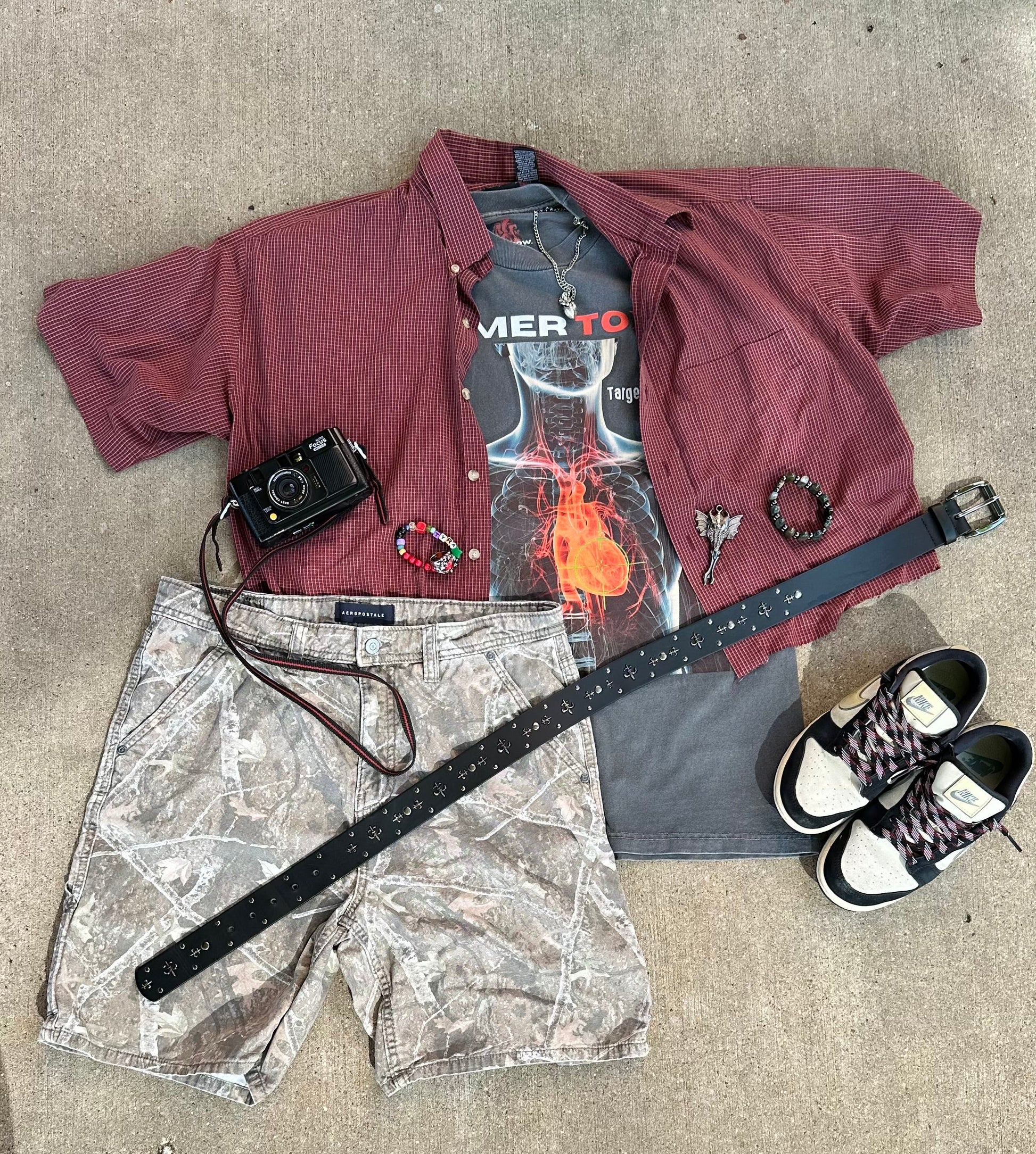 Flat lay outfit with Heat Scan Targeted Heart Tee styled with red shirt, camera, bracelets, belt, shorts, and sneakers.